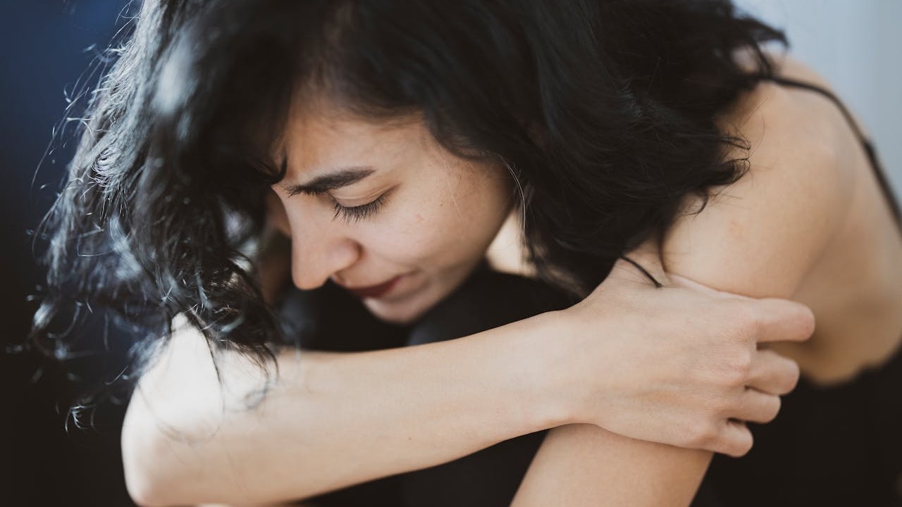 A woman sits on the floor, looking thoughtful and emotionally weighed down by a major family decision